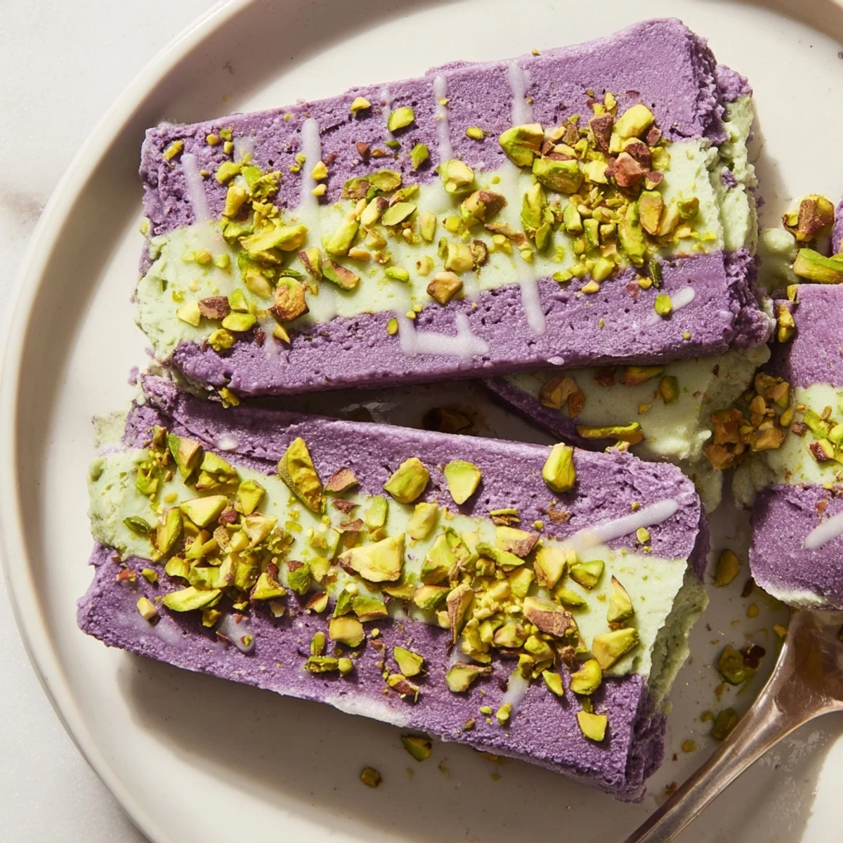 Vibrant ube & pistachio ice cream bars, drizzled with sweetened condensed milk, served chilled.  