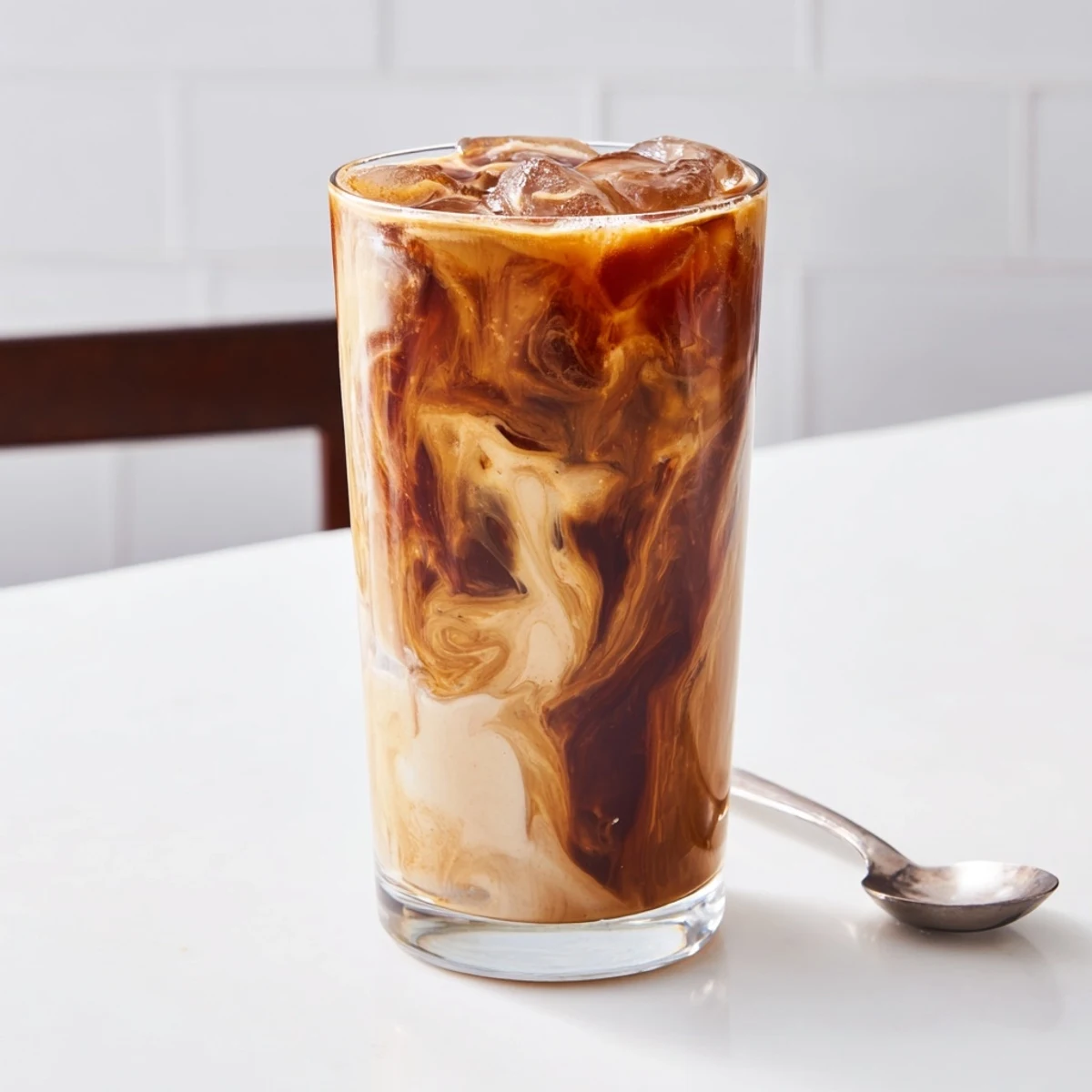 Refreshing tahini iced coffee topped with plant-based milk for a vegan treat.