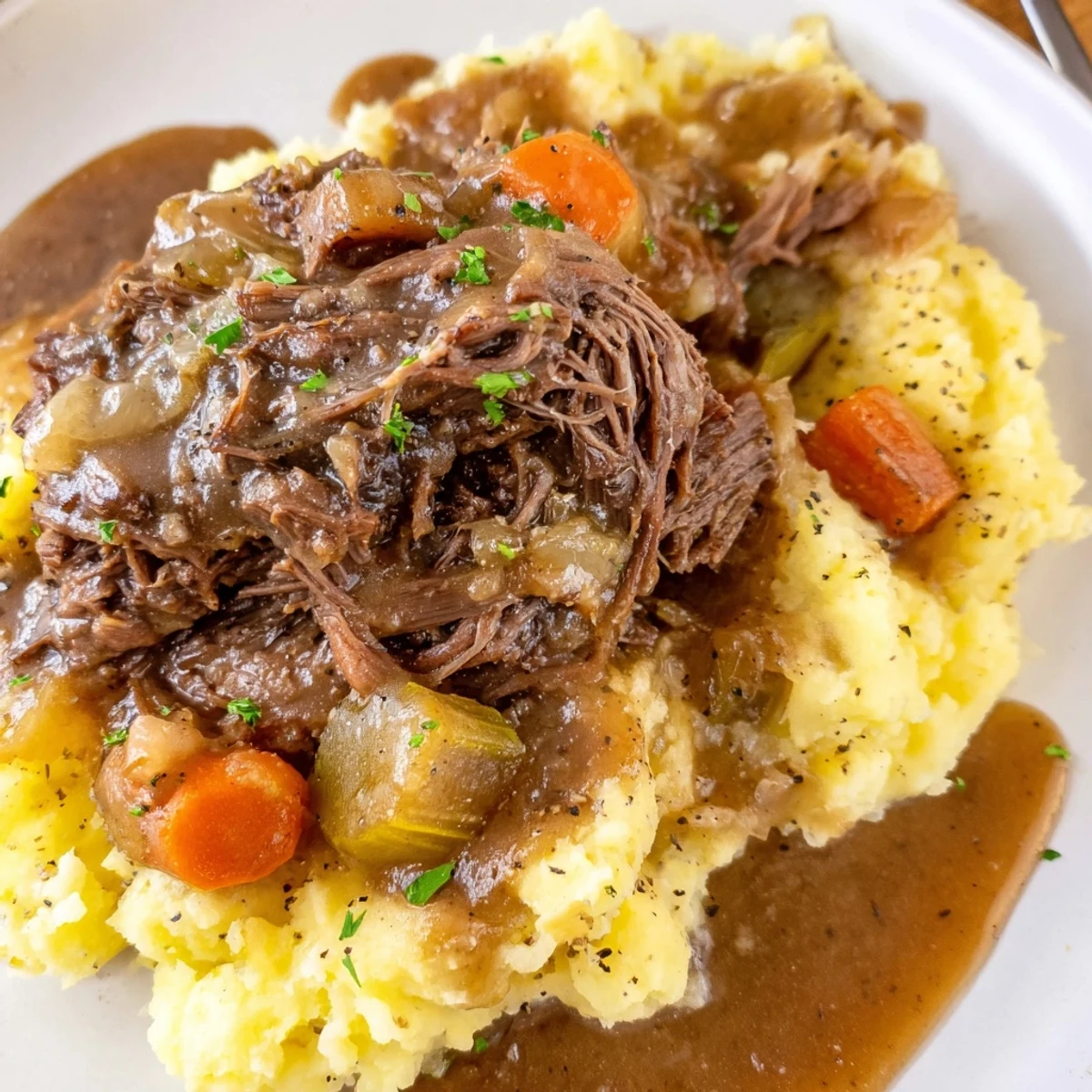 Slow Cooker Pot Roast with Mashed Potatoes, served with savory gravy and fresh herbs.