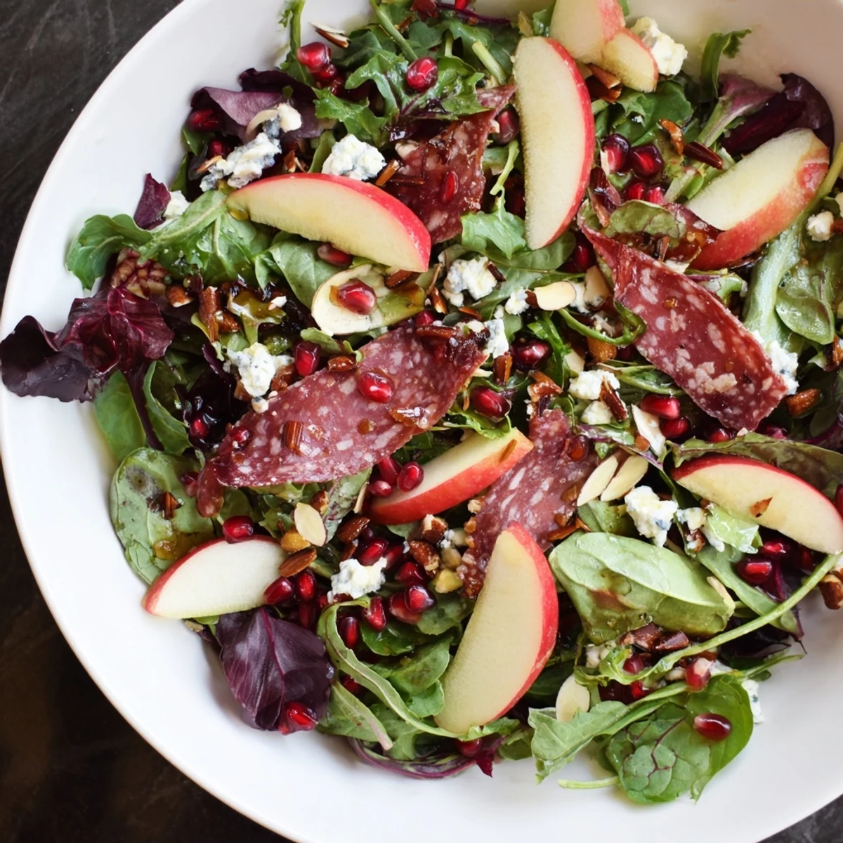 Hot Girl Christmas Salad with salami, a colorful, hearty salad with pomegranate seeds and creamy cheese.