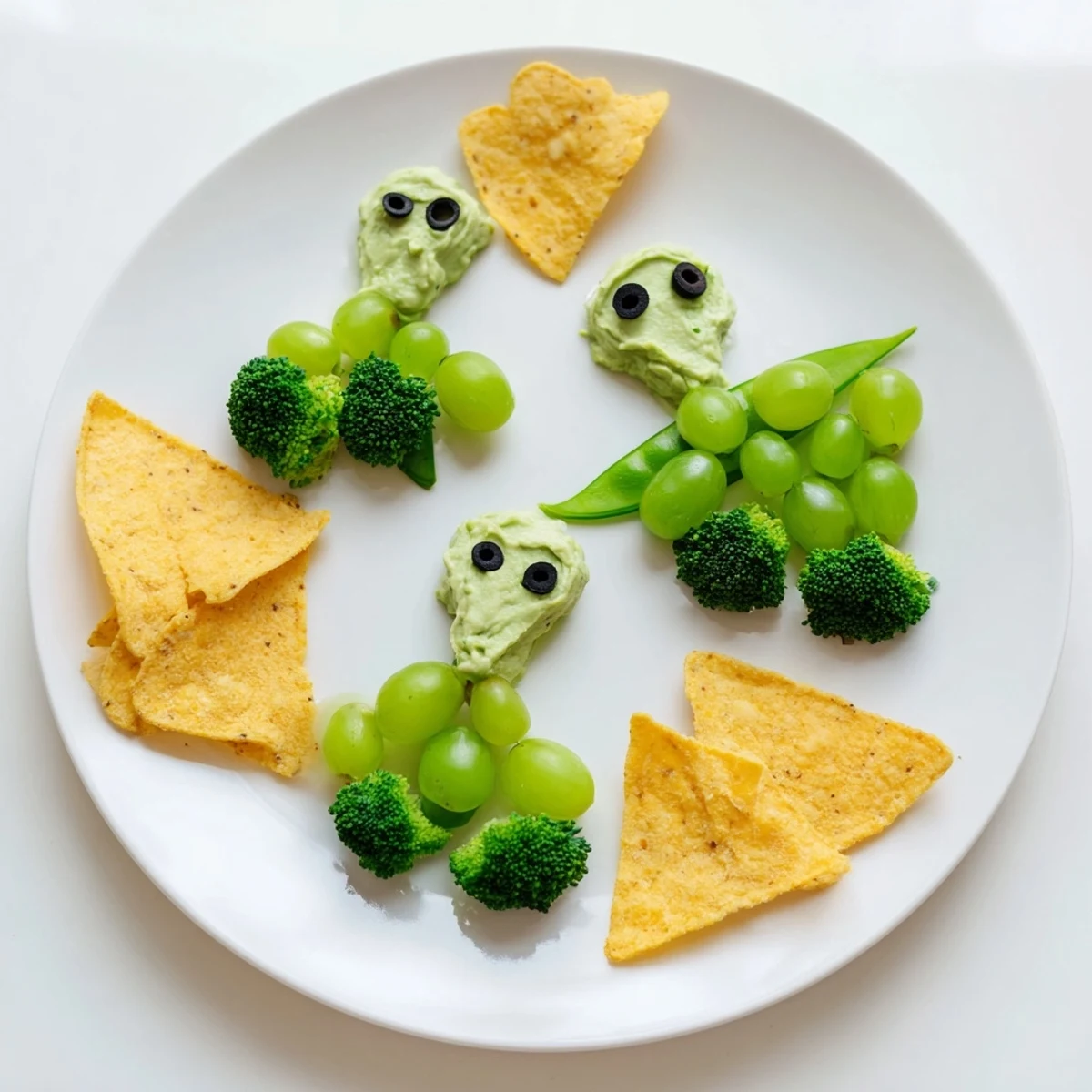 These fun Attack d'Extraterrestres Snacks Verts feature creamy guacamole and olive eyes on fresh, crunchy vegetables.