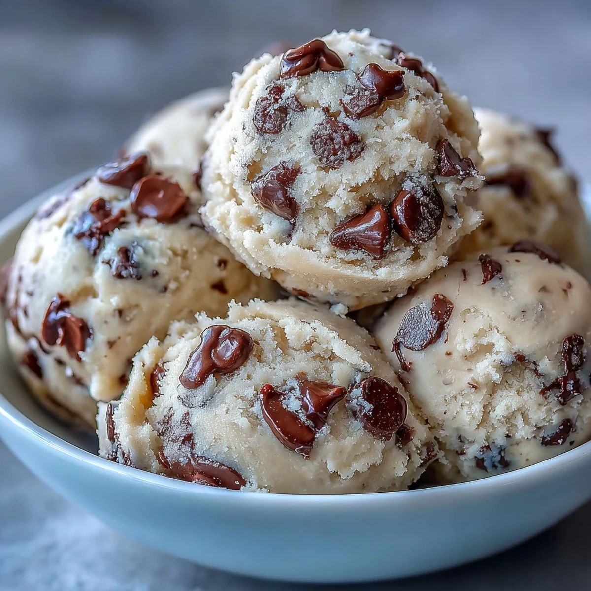 A spoonful of Greek Yogurt Cookie Dough studded with mini chocolate chips on a marble board.