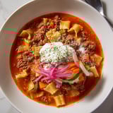 Delicious lasagne soup garnished with colorful pickled veggies for a fresh twist.