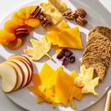 A close-up of a festive Thanksgiving Leaf Fall board with colorful cheese and cracker leaves ready.