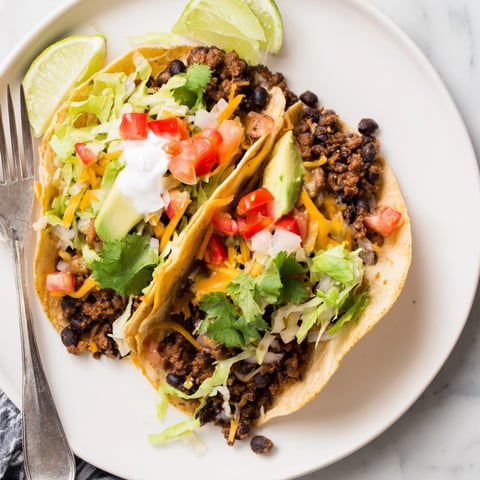 Golden tortillas piled high with Cheesy Cajun Black Bean Tacos, ready for topping and serving.