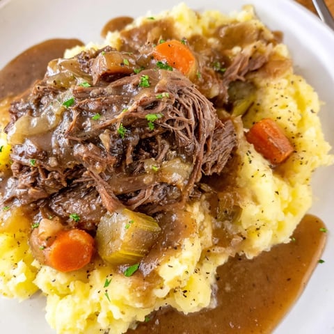Slow Cooker Pot Roast with Mashed Potatoes, served with savory gravy and fresh herbs.