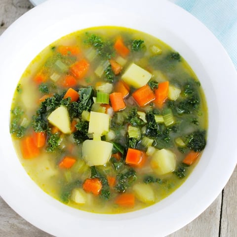 Steaming bowlful of Vegetarian Potato-Kale Soup, showcasing vibrant green kale and tender potatoes.