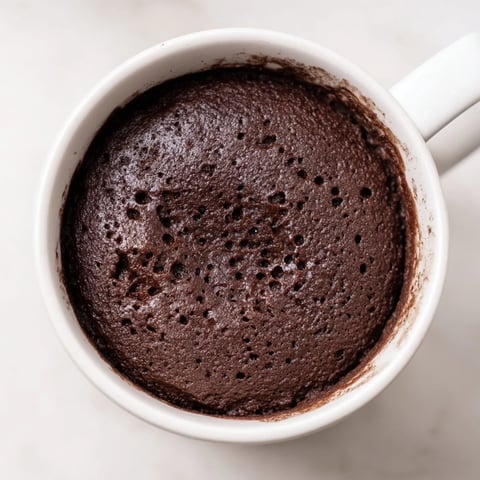 Steaming hot microwave mug cake, a quick chocolate dessert, ready in a single serving.