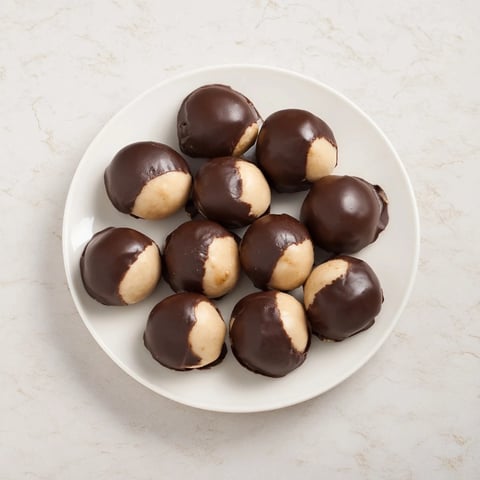 Creamy peanut butter buckeyes, partially dipped in chocolate, perfect for holiday dessert tables.