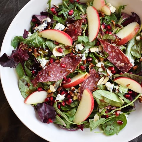 Hot Girl Christmas Salad with salami, a colorful, hearty salad with pomegranate seeds and creamy cheese.