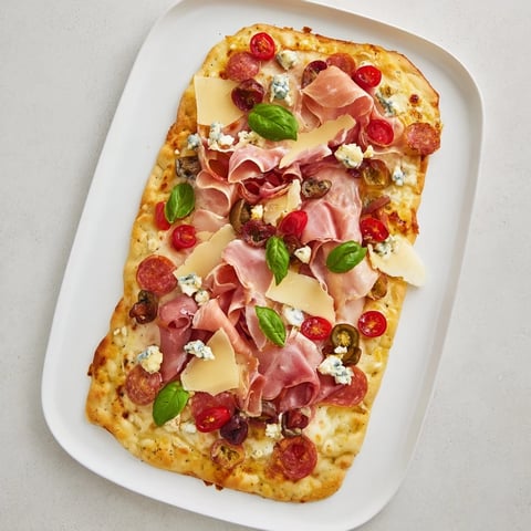 The Rustic Raft appetizer with layers of meats, cheeses, and colorful fresh garnishes.
