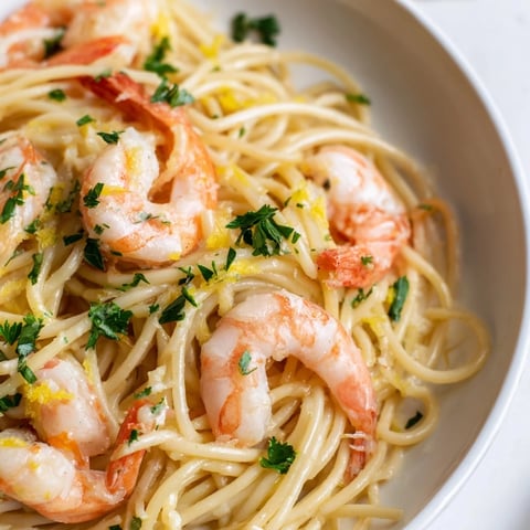 Bright, juicy shrimp glistening in a lemon garlic butter sauce, tossed with al dente spaghetti and fresh parsley on a white plate.