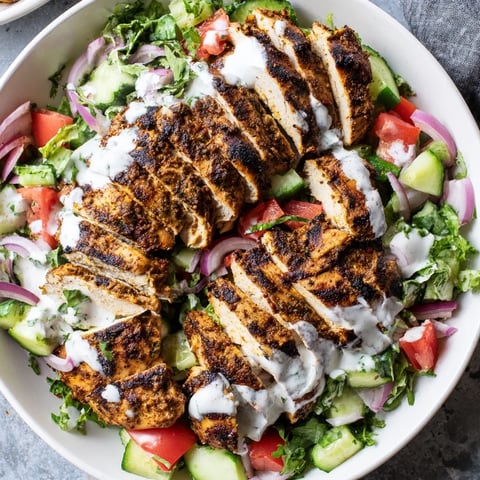 Colorful Chicken Shawarma Salad in a white bowl showcases spiced grilled chicken slices atop crisp cucumber, tomato, and fresh greens.