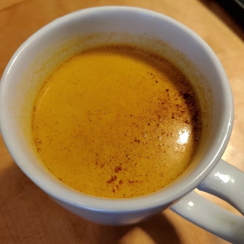 Creamy golden milk, infused with turmeric and ginger, steams gently in a rustic mug next to warm oat cookies.  