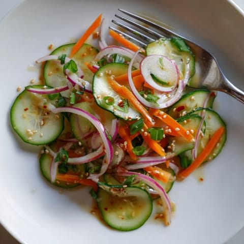 Cucumber salad remix featuring thinly sliced veggies drizzled with savory sesame dressing.  