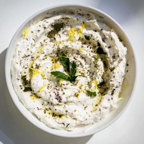 Fresh herbs dot the surface of this whipped feta appetizer, inviting a delicious taste.