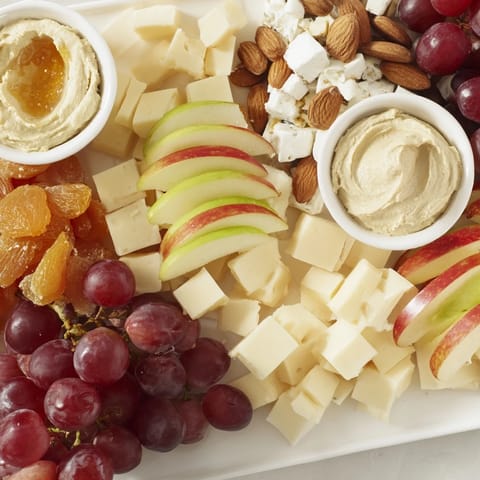 A fully-loaded Picnic Basket Snack Board, featuring fresh grapes, cheese, and crunchy crackers ready to enjoy.