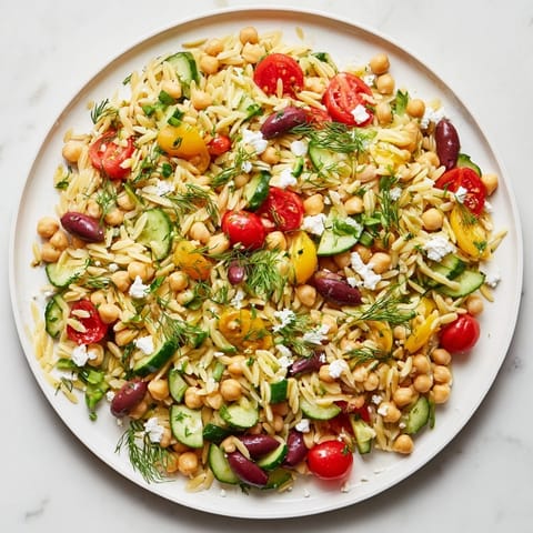 Tossed Greek Lemon-Orzo Bean Salad with bright tomatoes, smelling of zesty lemon vinaigrette.
