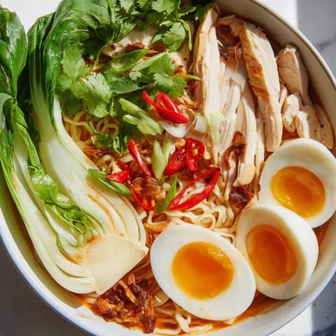 A flavorful Thai Miso Ramen Bowl showcases rich broth surrounding noodles, with crispy shallots for texture.