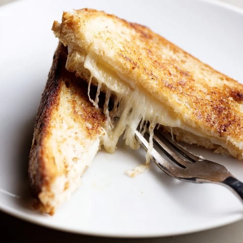 Freshly melted Three-Cheese Grilled Cheese oozes mozzarella, cheddar, and provolone from a crispy, buttery sourdough crust.