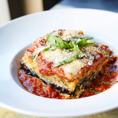 Golden-brown Eggplant Parmesan Lasagna, layered with creamy cheese and rich marinara sauce, steaming hot.