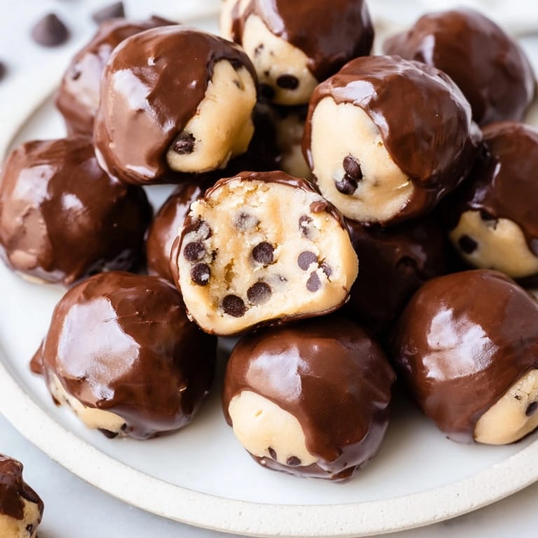 Delectable no-bake Cookie Dough Bites glistening with smooth semi-sweet chocolate, chilled to perfection.