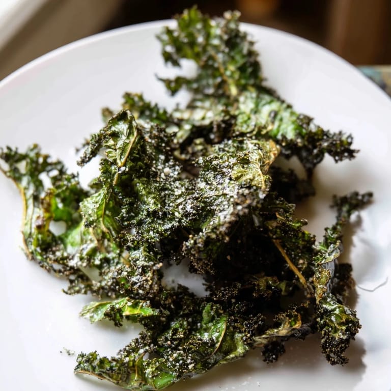 Oven-baked kale chips, perfectly seasoned and lightly oiled, offering a delicious, guilt-free treat.