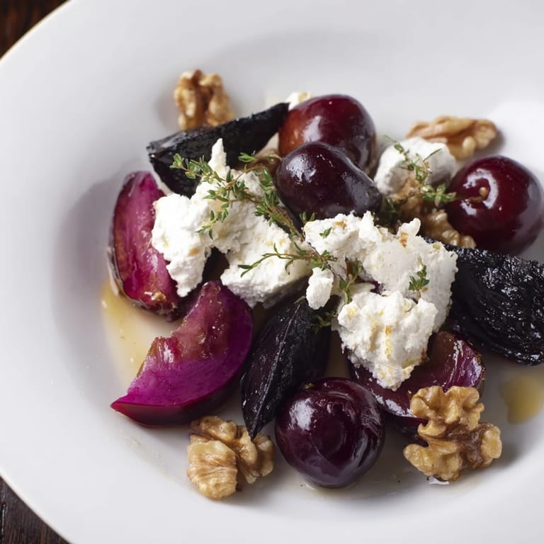 Vibrant Midnight Orchard appetizer: ripe plums, grapes, and ash-covered goat cheese artfully arranged.