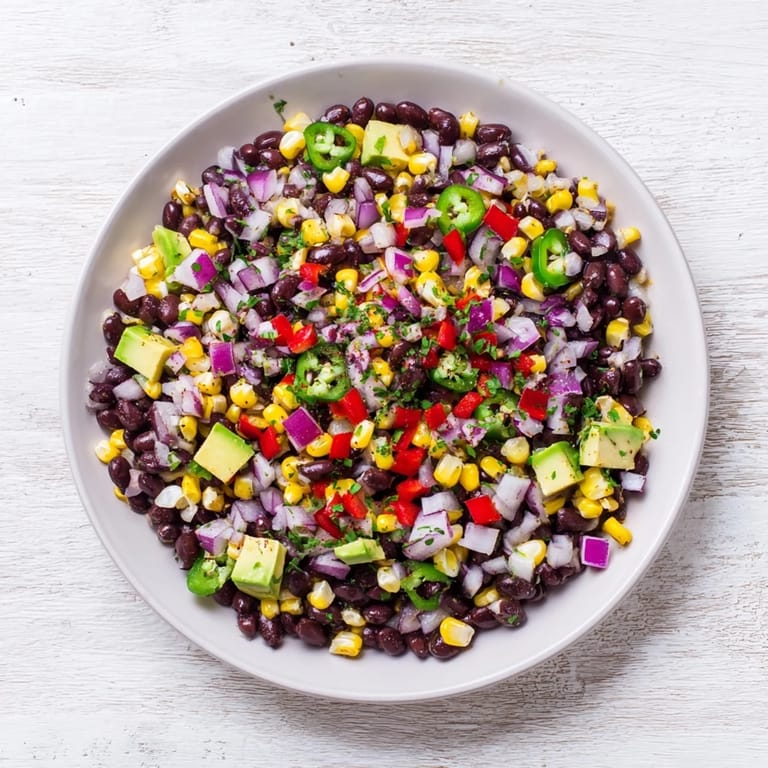 Close-up of fresh Southwestern Black Bean and Corn Salad, drizzled with lime dressing.