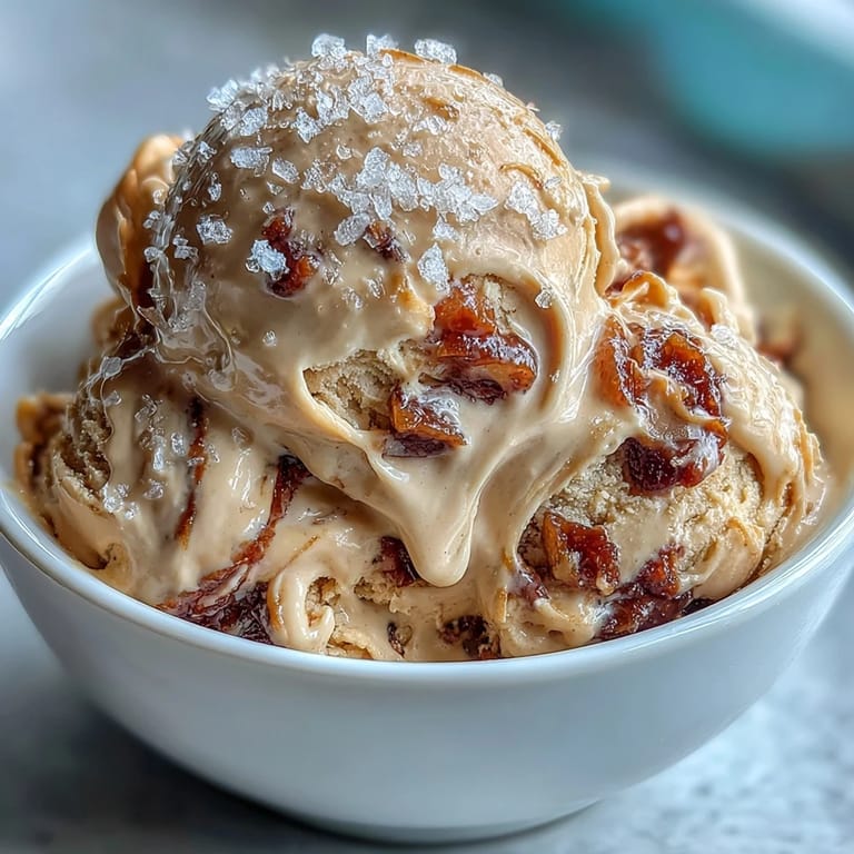 Creamy tahini ice cream with Medjool dates and a sprinkle of flaky sea salt, served in a chilled bowl. Rich, nutty flavors and sweet date swirls create a Middle Eastern-inspired dessert. Velvety tahini ice cream topped with homemade date compote and a touch of sea salt for a balanced sweet and savory treat. Silky tahini ice cream base with luscious Medjool date ribbons, garnished with sea salt for a gourmet frozen dessert experience.