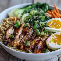 Healthy Miso Chicken Noodle Bowls in a white ceramic bowl, featuring tender chicken, chewy soba noodles, crisp bok choy, and a savory miso broth topped with sesame seeds.