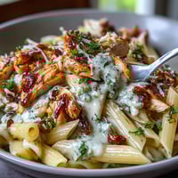 Creamy Crockpot Mississippi Chicken Pasta in a slow cooker with tender shredded chicken and tangy pepperoncini peppers.