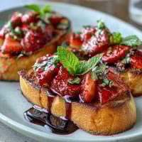 Fresh strawberry bruschetta with balsamic and mint, toasted baguette topped with juicy berries, fragrant herbs, and tangy glaze.